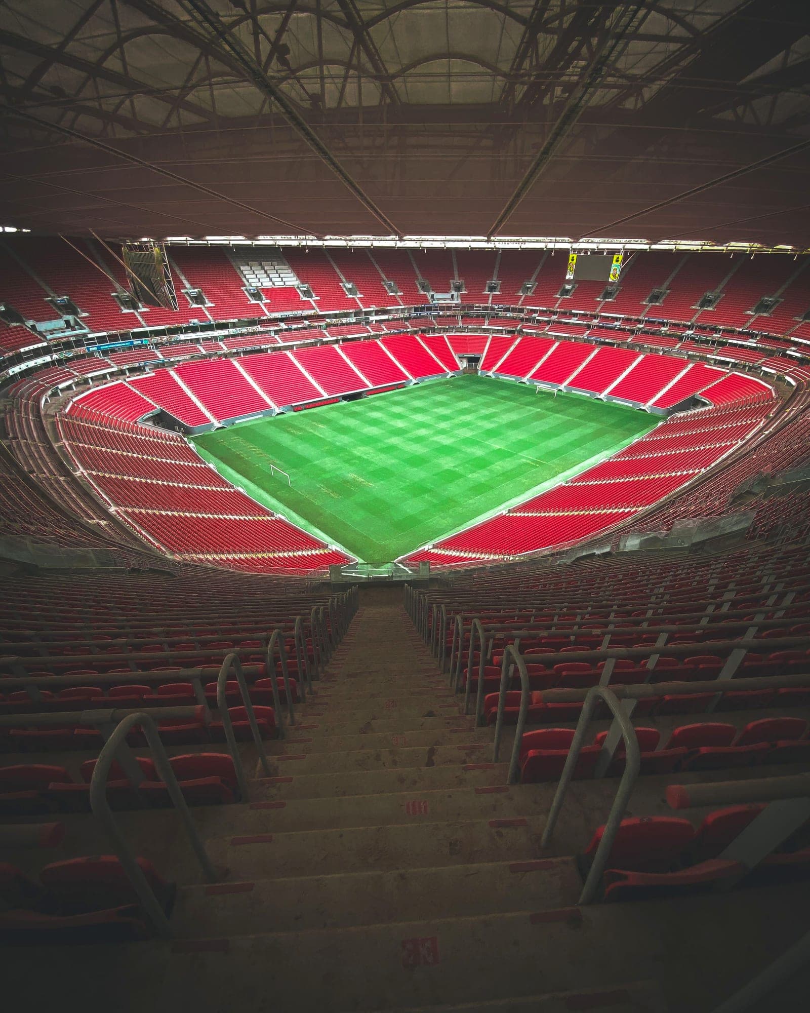 Empty stadium with rows of red seats around a freshly striped pitch