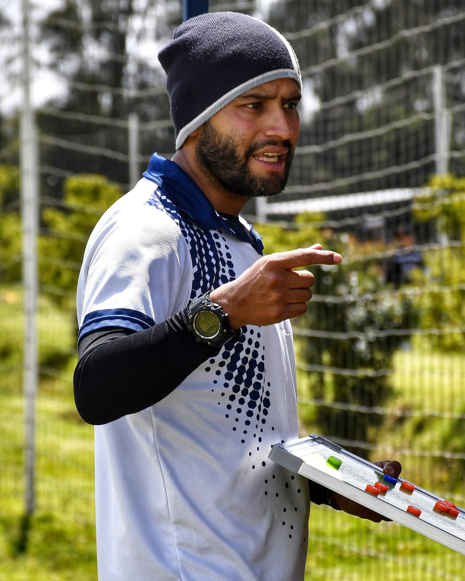 Coach pointing out instructions while holding a magnetic tactics board